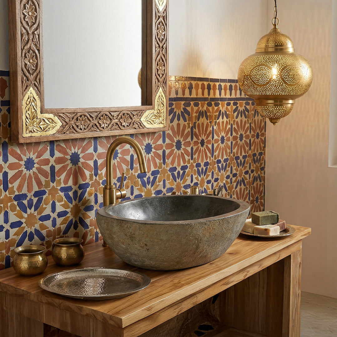 Flussstein Waschbecken im orientalischen Bad auf Holzkonsole, kombiniert mit Messingarmatur, Mosaikfliesen und warmem Licht