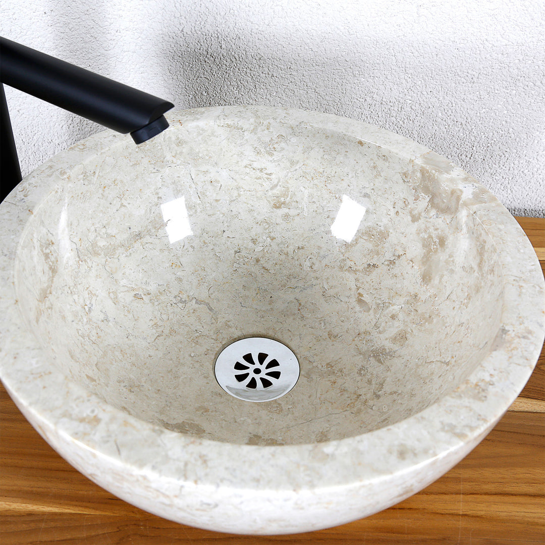 Detailansicht eines runden Aufsatzwaschbeckens aus hellem Naturstein mit polierter Innenfläche und zentralem Ablauf