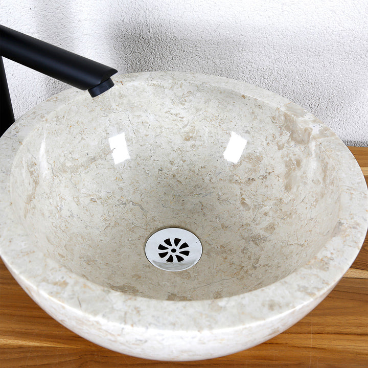 Detailansicht eines runden Aufsatzwaschbeckens aus hellem Naturstein mit polierter Innenfläche und zentralem Ablauf