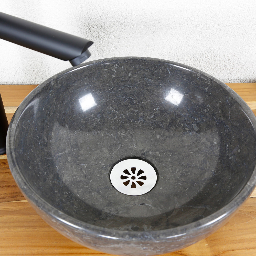 Rundes Aufsatzwaschbecken aus Naturstein in Detailansicht mit polierter Innenfläche, Edelstahl-Ablauf und Armatur