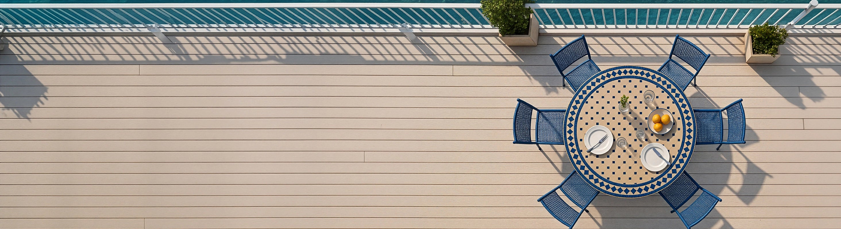 Mosaiktische Ø120 – Großer runder Mosaiktisch Ø120 cm mit blauen Zellige-Fliesen und mehreren Stühlen aus der Vogelperspektive auf Terrasse mit Meerblick