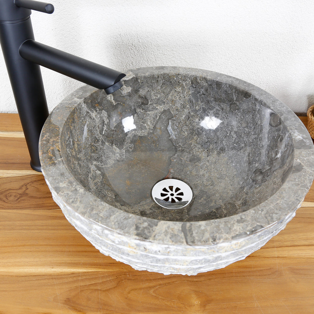 Rundes Aufsatzwaschbecken aus Naturstein mit polierter Innenfläche und strukturierter Außenkante auf Holzplatte