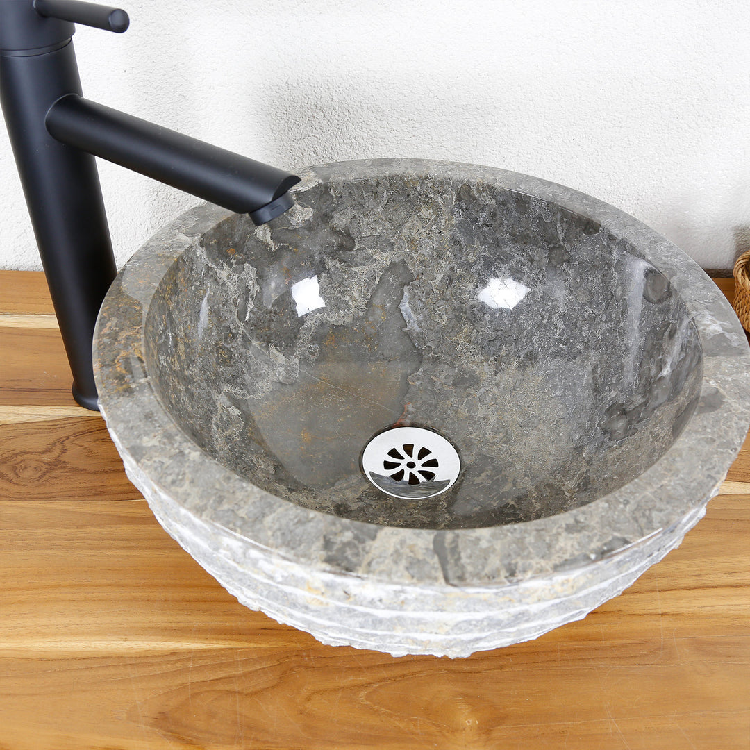 Rundes Aufsatzwaschbecken aus Naturstein mit polierter Innenfläche und strukturierter Außenkante auf Holzplatte