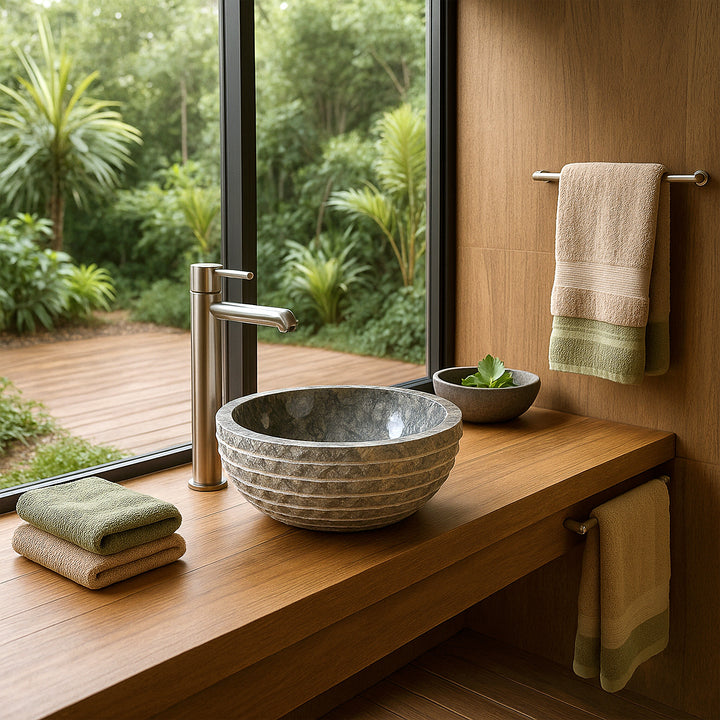 Rundes Aufsatzwaschbecken aus Stein auf Waschtisch, modernes Bad mit Fensterblick ins Grüne, Handtücher und Pflanze