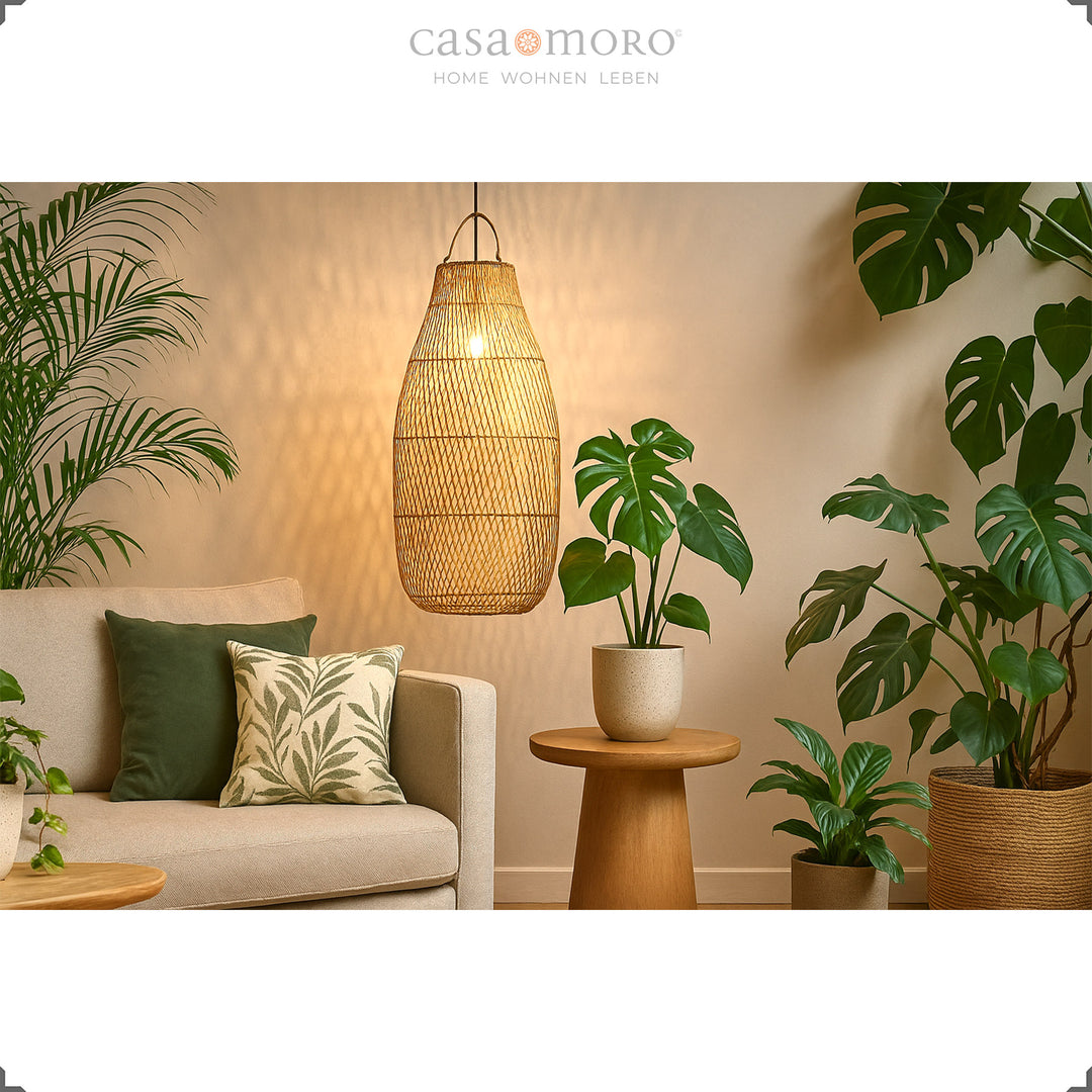 Große Rattan Deckenleuchte über Sofa im Wohnzimmer mit vielen Grünpflanzen und warmem Licht