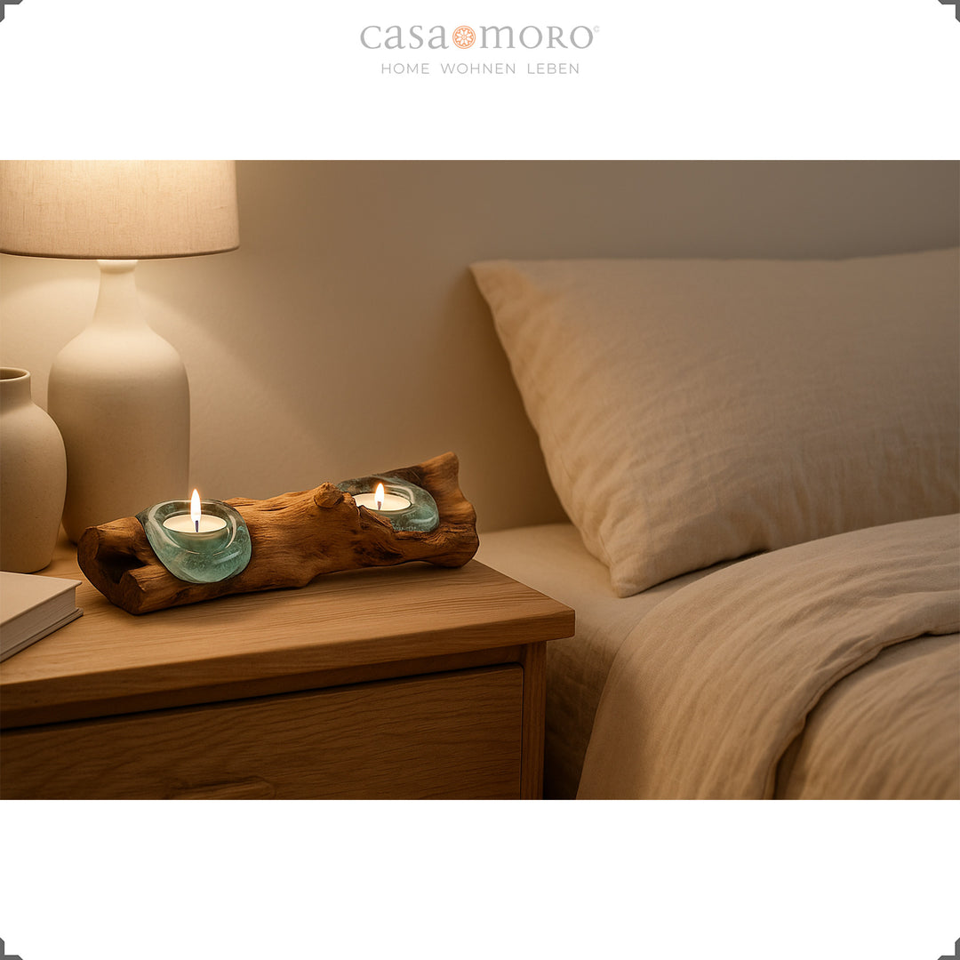 Länglicher Teelichthalter aus Glas und Wurzelholz auf einem Nachttisch, sein sanftes Licht schafft eine beruhigende Schlafzimmeratmosphäre.